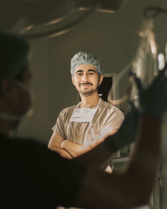 cta-02 A confident surgeon in scrubs, smiling in an operation room, highlighting professionalism.