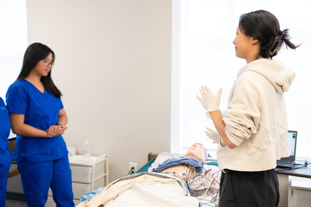 programs-03 Nursing students engage in hands-on training with a medical dummy in a clinical setting.