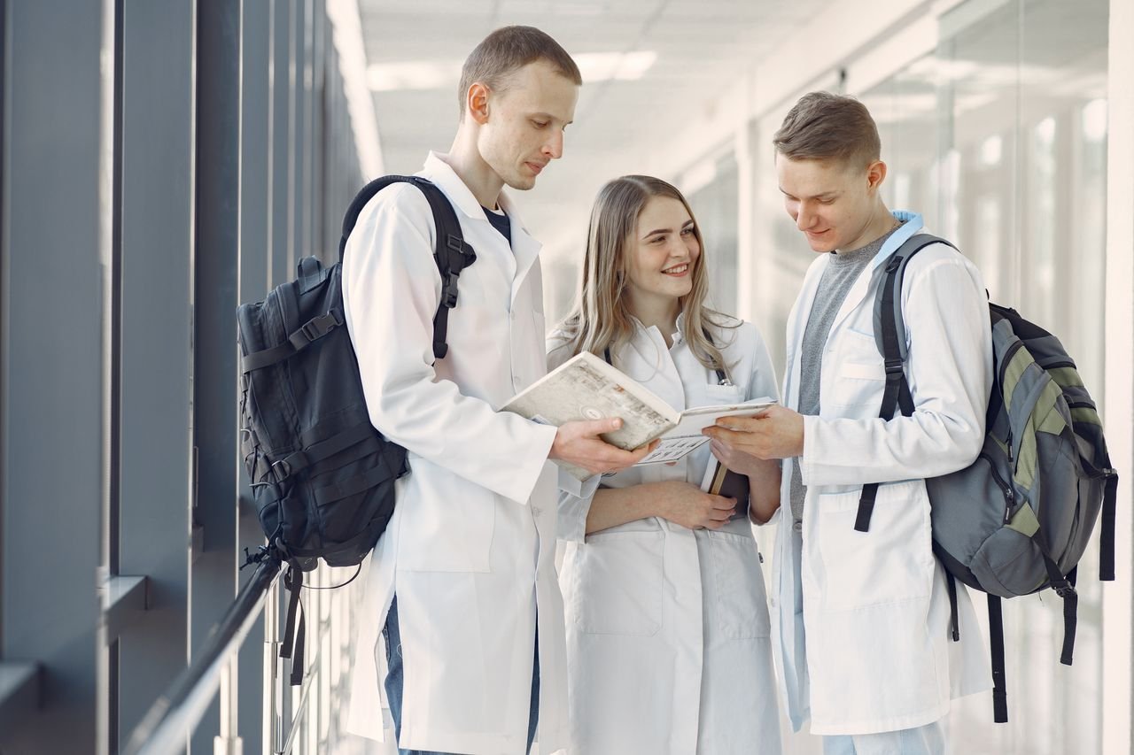 programs-01 A group of medical students in white coats studying together in a hospital hallway.