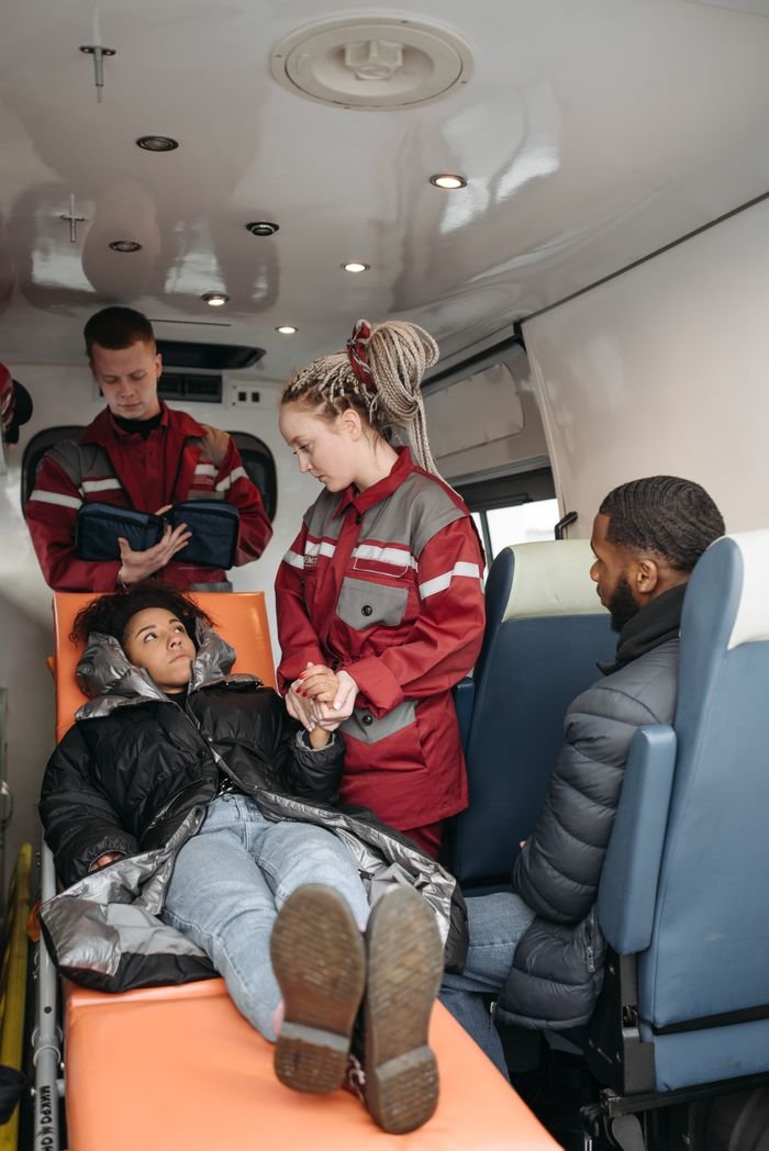 gallery-img-02 Emergency medical team aids patient on stretcher inside ambulance, fostering care.
